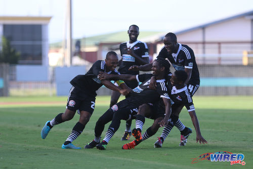 Photo: Central FC forward Jason Marcano (centre) is dragged to the ground by his teammates after his opening goal against North East Stars at the Mannie Ramjohn Stadium in Marabella on 8 May 2016. Marcano scored twice as Central cruised to a 4-0 win to complete their successful defence of the league title. (Courtesy Chevaughn Christopher/Wired868)