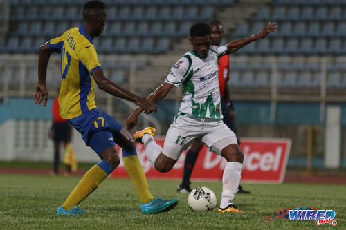 Photo: W Connection utility player Aikim Andrews (right) prepares to unleash a shot while Defence Force winger Ross Russell Jr looks on during the Digicel Pro Bowl final at the Ato Boldon Stadium on 27 May 2016. Andrews scored but Defence Force won 2-1. (Courtesy Chevaughn Christopher/Wired868)