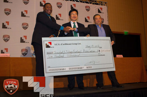 Photo: TTFA president David John-Williams (left) shakes hands with a Shanghai Group of Companies representative on a TT$600,000 deal to play China. (Courtesy TTFA Media)