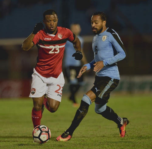 Photo: Trinidad and Tobago midfielder Jomal Williams (left) takes the ball past Uruguay defender Alvaro Pereira during friendly international action at the Centenario Stadium in Montevideo on 27 March 2016. Uruguay won 3-1. (Copyright Miguel Rojo/AFP 2016)