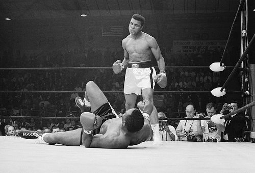 Photo: Muhammad Ali (right), then Cassius Clay, glares at fallen heavyweight champion Sonny Liston. (Copyright Entrepello.com)