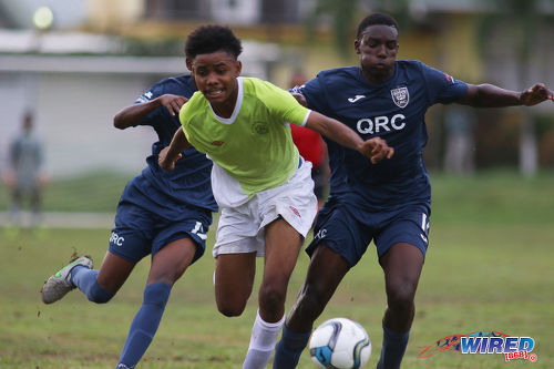 Photo: St Augustine player Tajh Devenish (centre) tries to hold off QRC's Miguel Williams during SSFL Premier Division action at the QRC grounds on 8 September 2016. (Courtesy Chevaughn Christopher/Wired868)