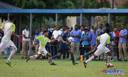 Photo: QRC midfielder Keyshawn Villafana (centre) runs at St Augustine opponents during SSFL Premier Division action at the QRC grounds on 8 September 2016. (Courtesy Chevaughn Christopher/Wired868)