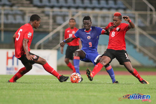 Photo: Haiti forward Nael Elysee (centre) tries to escape from the attentions of Trinidad and Tobago midfielder Jodel Brown (right) and defender Jesse Williams during 2017 World Cup qualifying action in Couva on 17 September 2016. Elysee scored the opener as Haiti won 2-0. (Courtesy Chevaughn Christopher/Wired868)