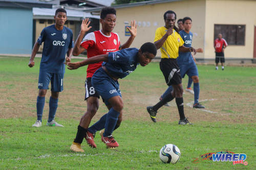 Photo: St Anthony's College captain Jules Lee (centre) tries to avoid contact with a QRC opponent during SSFL action at QRC grounds on 26 October 2016. (Courtesy Nicholas Williams/Wired868)