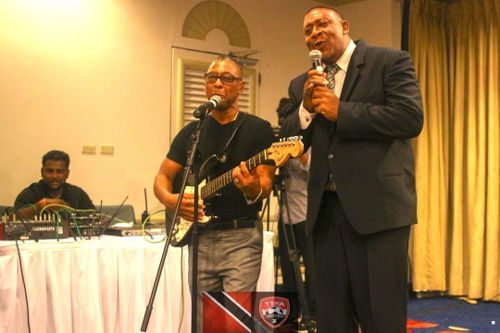 Photo: Trinidad and Tobago Football Association (TTFA) president David John-Williams (right) performs a duet with former Calypso Monarch, Cro Cro, at the launch of the National Elite Youth Development Program at the Trinidad Hilton on 14 October 2016. (Copyright TTFA Media)