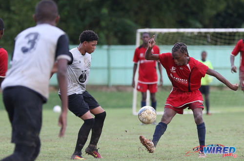 Photo: A mysterious Malick Secondary playmaker (right)--his name was incorrectly written as Shaquille Mayers on the team list--performs a clever trick, as he flicks the ball over the head of Trinity College East attacker Kishon Hackshaw during Championship Big 5 Play Off action in Trincity on 6 November 2016. (Courtesy Sean Morrison/Wired868)