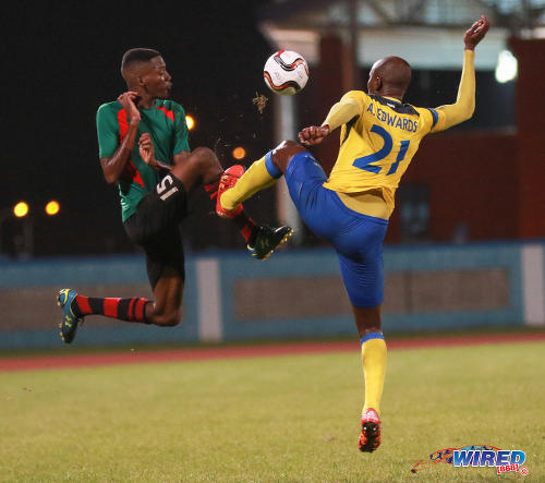 Photo: San Juan Jabloteh defender Jerome Isaiah McIntyre (left) finds himself on the end of a crunching tackle from Defence Force left back Akile Edwards during Pro League action at the Ato Boldon Stadium on 18 September 2016. (Courtesy Sean Morrison/Wired868)