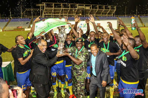 Photo: Defence Force players and staff celebrate with Pro League CEO Dexter Skeene (centre) after beating Ma Pau Stars to the First Citizens Bank Cup title at the Hasely Crawford Stadium on 2 December 2016. (Courtesy Sean Morrison/Wired868)