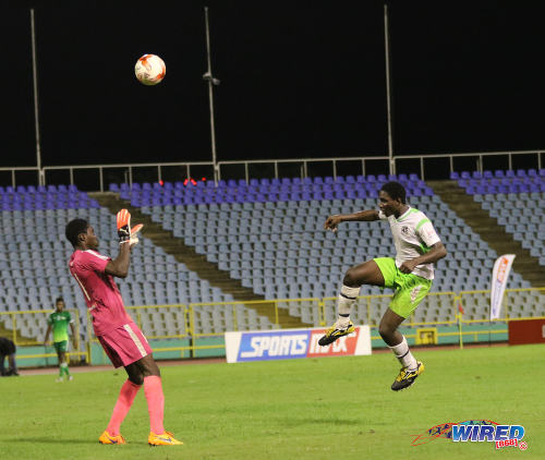 Photo: San Juan North striker Renaldo Boyce (right) lobs the ball over Trinity College Moka goalkeeper Desean Bowen during National Intercol semifinals action at the Hasely Crawford Stadium, Port of Spain on 30 November 2016. (Courtesy Sean Morrison/Wired868)