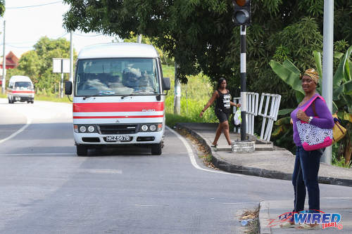 Photo: A commuter waits for a maxi taxi on the Bus Route in D'Abadie. (Courtesy Sean Morrison/Wired868)