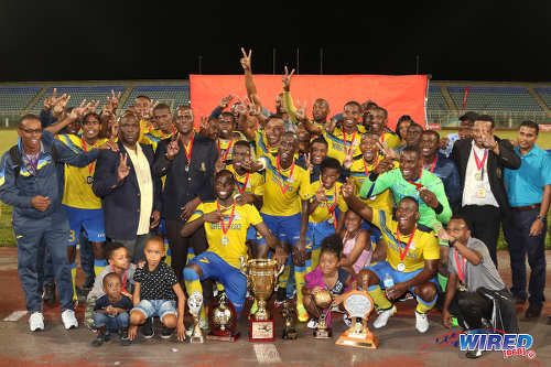 Photo: Defence Force striker Devorn Jorsling (stooping, second from right) and his teammates celebrate after retaining their Pro Bowl title at the Ato Boldon Stadium on 19 February 2017. Defence Force defeated Central FC 5-3 on kicks from the penalty spot after a 2-2 tie. (Courtesy Sean Morrison/Wired868)