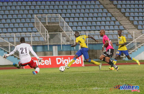 Photo: Defence Force striker Jamille Boatswain (second from left) squeezes his shot past Central FC goalkeeper Jan-Michael Williams (left) while defender Julius James (second from right) and Jerwyn Balthazar look on during the Pro Bowl final at the Ato Boldon Stadium on 19 February 2017. Defence Force won 5-3 on kicks from the penalty mark after a 2-2 draw. (Courtesy Sean Morrison/Wired868)