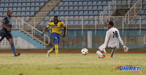 Photo: Defence Force striker Jamille Boatswain (centre) prepares to steer his hattrick goal past Police FC goalkeeper Adrian Foncette (right) during the Pro Bowl semifinals at the Ato Boldon Stadium on 12 February 2017. Defence Force won 4-0. (Courtesy Sean Morrison/Wired868)