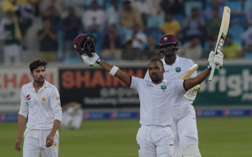 Photo: West Indies batsman Darren Bravo (right) raises his bat and helmet to celebrate a century against Pakistan as team captain Jason Holder (back) and Pakistani bowler Mohammad Amir look on during the final day of the first day-night Test between Pakistan and the West Indies at the Dubai International Cricket Stadium in the Gulf Emirate on 17 October 2016. (Copyright AFP 2017/Aamir Qureshi)