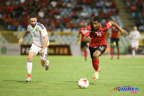 Photo: Trinidad and Tobago forward Willis Plaza (right) runs at Mexico winger Miguel Layun Mexico forward Javier Hernandez (right) tries unsuccessfully to evade a tackle from Trinidad and Tobago midfielder Kevan George during 2018 FIFA World Cup qualifying action at the Hasely Crawford Stadium in Port of Spain on 28 March 2017. (Courtesy Chevaughn Christopher/Wired868)