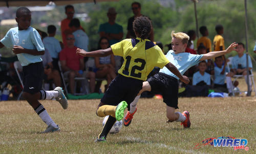 Photo: QPCC ‘1’ midfielder Cayden Trestrail (right) tries to play the ball around Trendsetter Hawks ‘2’ player Joshua Figaro (centre) during RBNYL North Zone Under-11 action at the Queen's Park Savannah on 22 April 2017. (Courtesy Sean Morrison/Wired868)