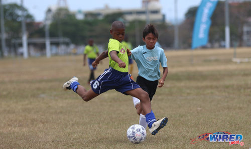 Photo: A Santa Cruz United FA player (left) takes aim during RBNYL North Zone Under-11 action against QPCC ‘2’ at the Queen's Park Savannah on 22 April 2017. Santa Cruz won 4-1. (Courtesy Sean Morrison/Wired868)