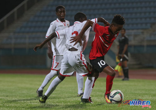 Photo: Trinidad and Tobago National Under-15 playmaker Josiah Edwards (right) tries to escape from Republic Bank XI defender Nathan Guy (centre) while his teammate Keron Manswell looks on during action at the Ato Boldon Stadium on 15 April 2017. (Courtesy Sean Morrison/Wired868)