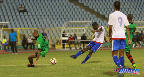 Photo: Portmore United captain and midfielder Ewan Grandison (centre) hammers home the equalising goal past San Juan Jabloteh defender Akeem Benjamin (left) during 2017 Caribbean Club Championship action at the Hasely Crawford Stadium on 18 May 2017. Jabloteh will meet Cibao FC from 8pm in Sunday's final. (Courtesy Sean Morrison/Wired868)