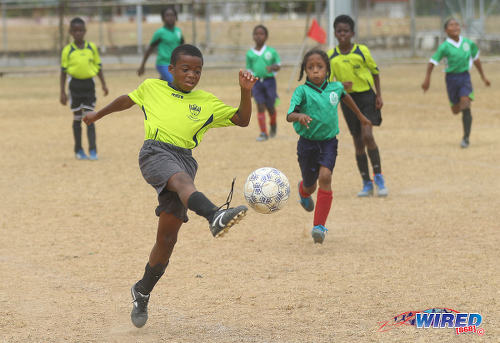 Photo: An Adrenaline FA player (left) clears the ball during RBNYL Under-11 action against Febeau Government Primary at Constantine Park in Macoya on 6 May 2017. (Courtesy Sean Morrison/Wired868)