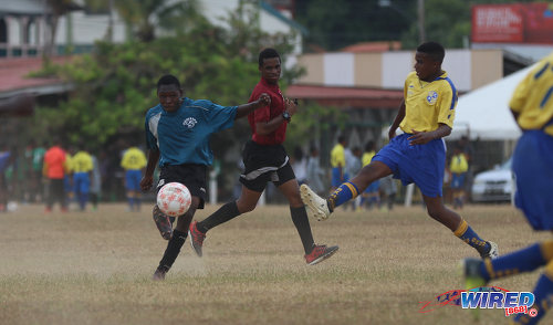 Photo: A Police FC player (left) takes a crack at the Defence Force/SKHY FC goal during RBNYL Under-15 action at Constantine Park in Macoya on 6 May 2017. (Courtesy Sean Morrison/Wired868)